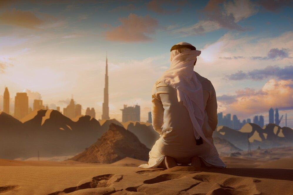 Blick auf Dubai Person, die im Sand sitzt und auf Dubai am Horizont blickt