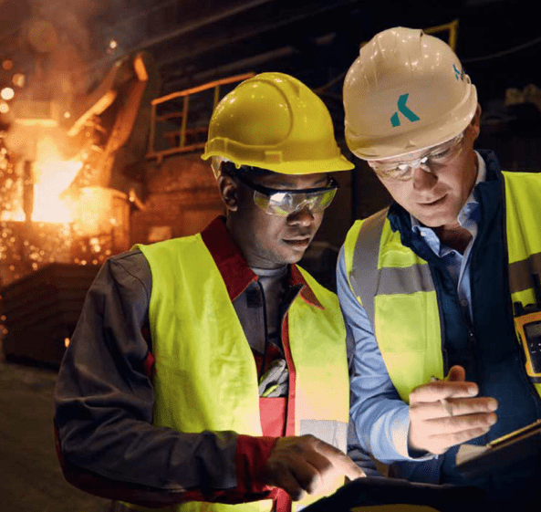 Two KrampeHarex employees look at a screen together in front of a fire