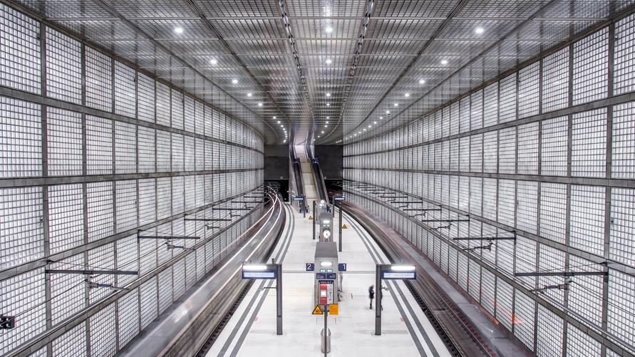 View of the completed platform at City Tunnel Leipzig featuring glass brick walls and a distinctive architectural lighting design.